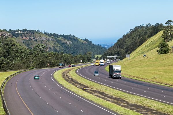 Many Vehicles on N3 Highway Entering and Leaving Pietermaritzburg Many vehicles on N3 highway entering and leaving Pietermaritzburg against distant blue city skyline landscape in South Africa